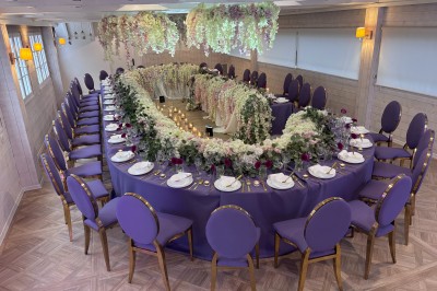 Salle de réception élégante avec décoration noire et dorée, tables dressées et bougies allumées.