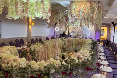 Salle de réception élégante avec décoration noire et dorée, tables dressées et bougies allumées.