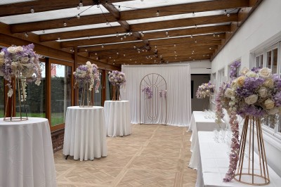 Salle de réception élégante avec décoration noire et dorée, tables dressées et bougies allumées.