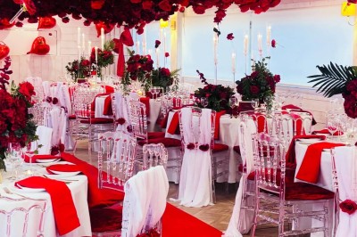 Salle de réception élégante avec décoration noire et dorée, tables dressées et bougies allumées.