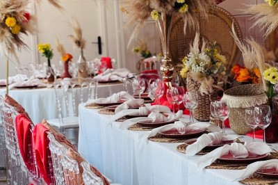 Salle de réception élégante avec décoration noire et dorée, tables dressées et bougies allumées.