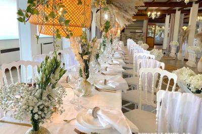 Table élégamment dressée avec vaisselle blanche et décorations florales, donnant sur une piste équestre en arrière-plan.