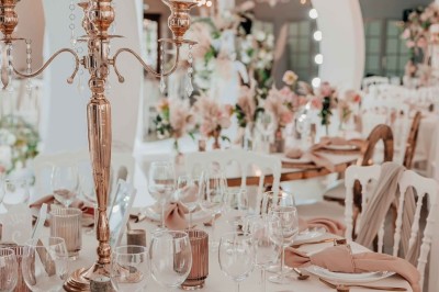 Salle de réception élégante avec décoration noire et dorée, tables dressées et bougies allumées.