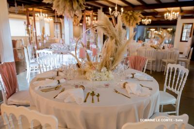 Table élégamment dressée avec vaisselle blanche et décorations florales, donnant sur une piste équestre en arrière-plan.