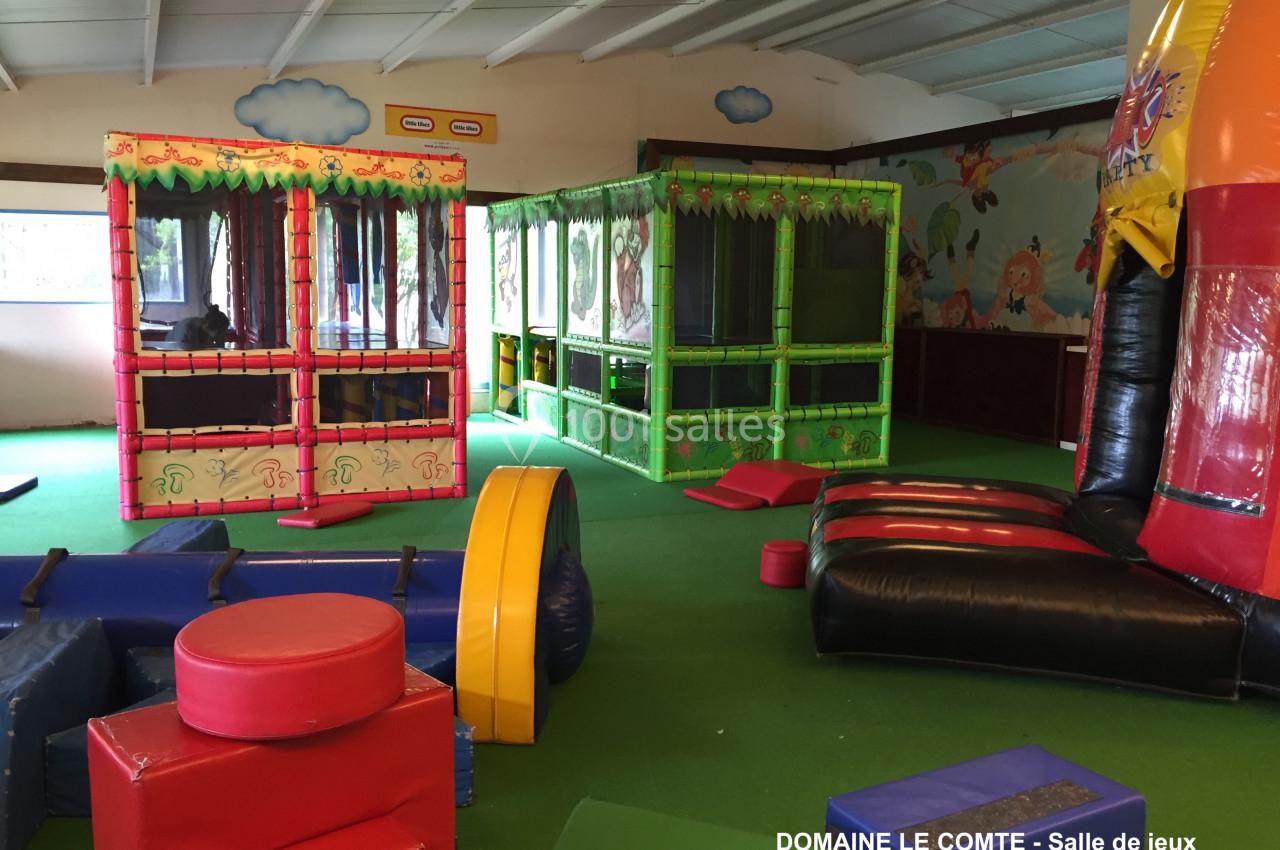 Salle de jeux intérieure avec structures gonflables colorées, modules en mousse et espaces de jeu pour enfants.