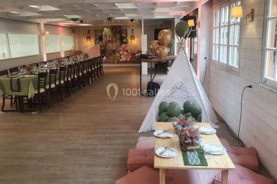 Table élégamment dressée avec vaisselle blanche et décorations florales, donnant sur une piste équestre en arrière-plan.