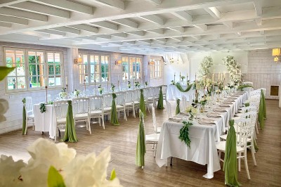 Salle de réception élégante avec décoration noire et dorée, tables dressées et bougies allumées.