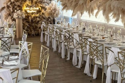 Salle de réception élégante avec décoration noire et dorée, tables dressées et bougies allumées.