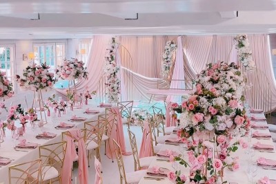 Salle de réception élégante avec décoration noire et dorée, tables dressées et bougies allumées.