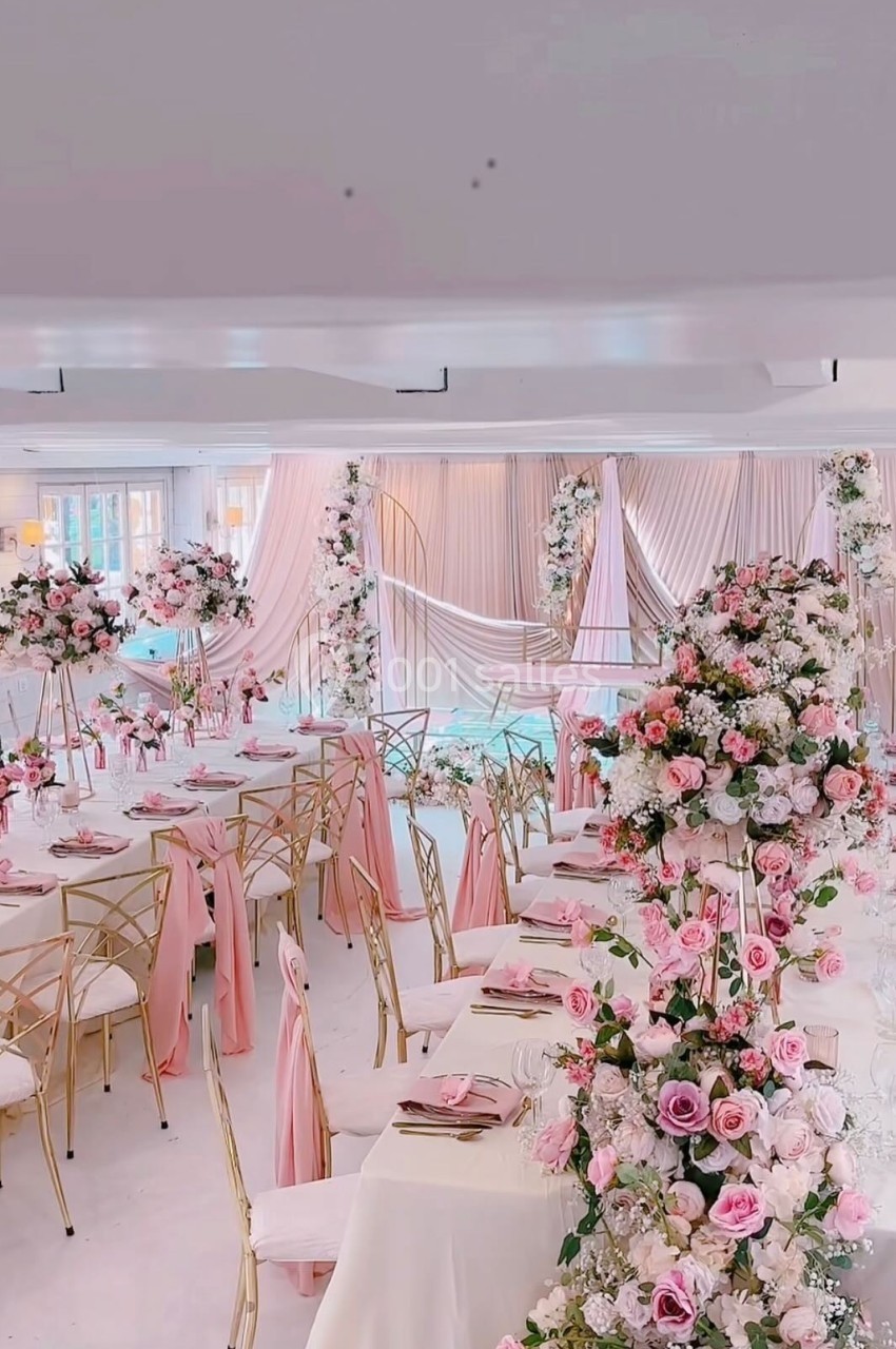 Salle de réception décorée avec des fleurs roses et blanches, nappes et chaises assorties dans une ambiance élégante.