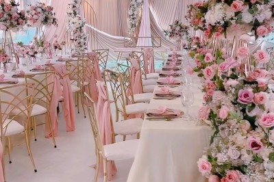 Salle de réception élégante avec décoration noire et dorée, tables dressées et bougies allumées.