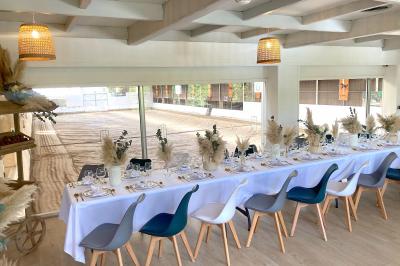 Salle de réception élégante avec décoration noire et dorée, tables dressées et bougies allumées.