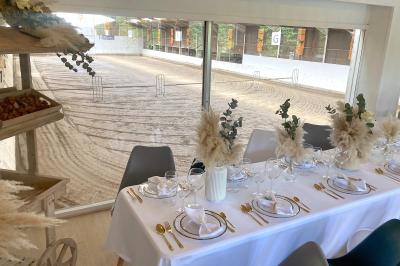 Salle de réception élégante avec décoration noire et dorée, tables dressées et bougies allumées.