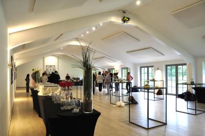 Salle de réunion lumineuse sous combles avec poutres apparentes, tables, chaises et écran de projection installé.