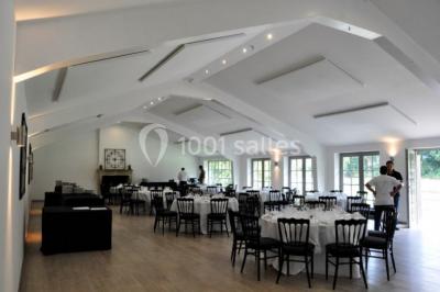 Vue d'un bâtiment en briques avec une tour, entouré d'arbres, d'une pelouse et d'un étang.