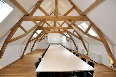 Vue d'un bâtiment en briques avec une tour, entouré d'arbres, d'une pelouse et d'un étang.