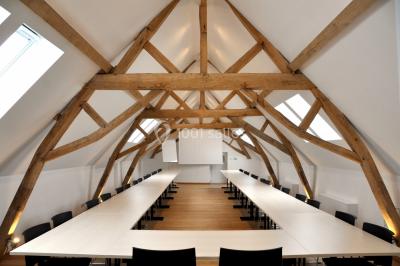 Vue d'un bâtiment en briques avec une tour, entouré d'arbres, d'une pelouse et d'un étang.