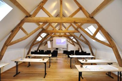 Vue d'un bâtiment en briques avec une tour, entouré d'arbres, d'une pelouse et d'un étang.