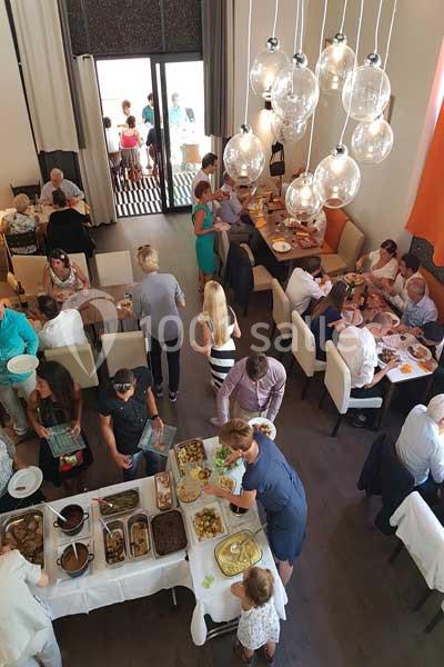 Vue d'une salle de restaurant animée avec des convives se servant à un buffet et d'autres assis à table.