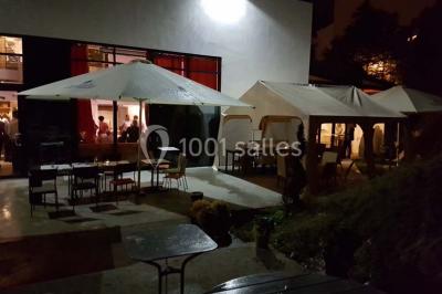 Des personnes se servent à un buffet varié disposé sur des tables rondes dans une salle lumineuse.