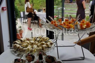 Des personnes se servent à un buffet varié disposé sur des tables rondes dans une salle lumineuse.