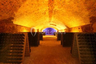 Miniature Location salle Épernay (Marne) - Château Comtesse Lafond #20 Des bouteilles de vin blanc dans une caisse en bois, avec un bar en bois et des tabourets en arrière-plan.