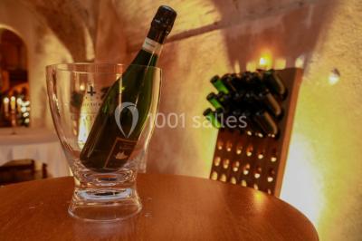Miniature Location salle Épernay (Marne) - Château Comtesse Lafond #23 Des bouteilles de vin blanc dans une caisse en bois, avec un bar en bois et des tabourets en arrière-plan.