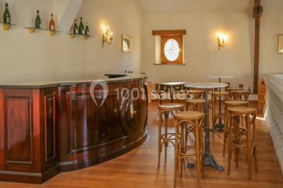 Miniature Location salle Épernay (Marne) - Château Comtesse Lafond #17 Des bouteilles de vin blanc dans une caisse en bois, avec un bar en bois et des tabourets en arrière-plan.