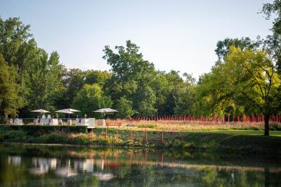Miniature Location salle Léognan (Gironde) - Château Larrivet Haut-Brion #13 Manoir blanc entouré d'arbres, reflété dans un étang, avec des piquets rouges au premier plan.