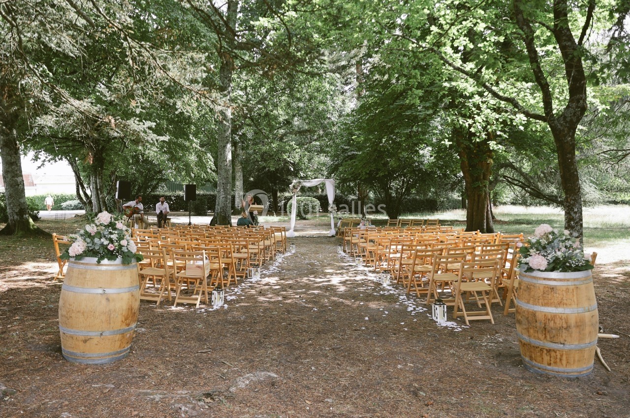 Chaises en bois disposées en rangées dans une clairière, avec une arche décorée pour une cérémonie en plein air.