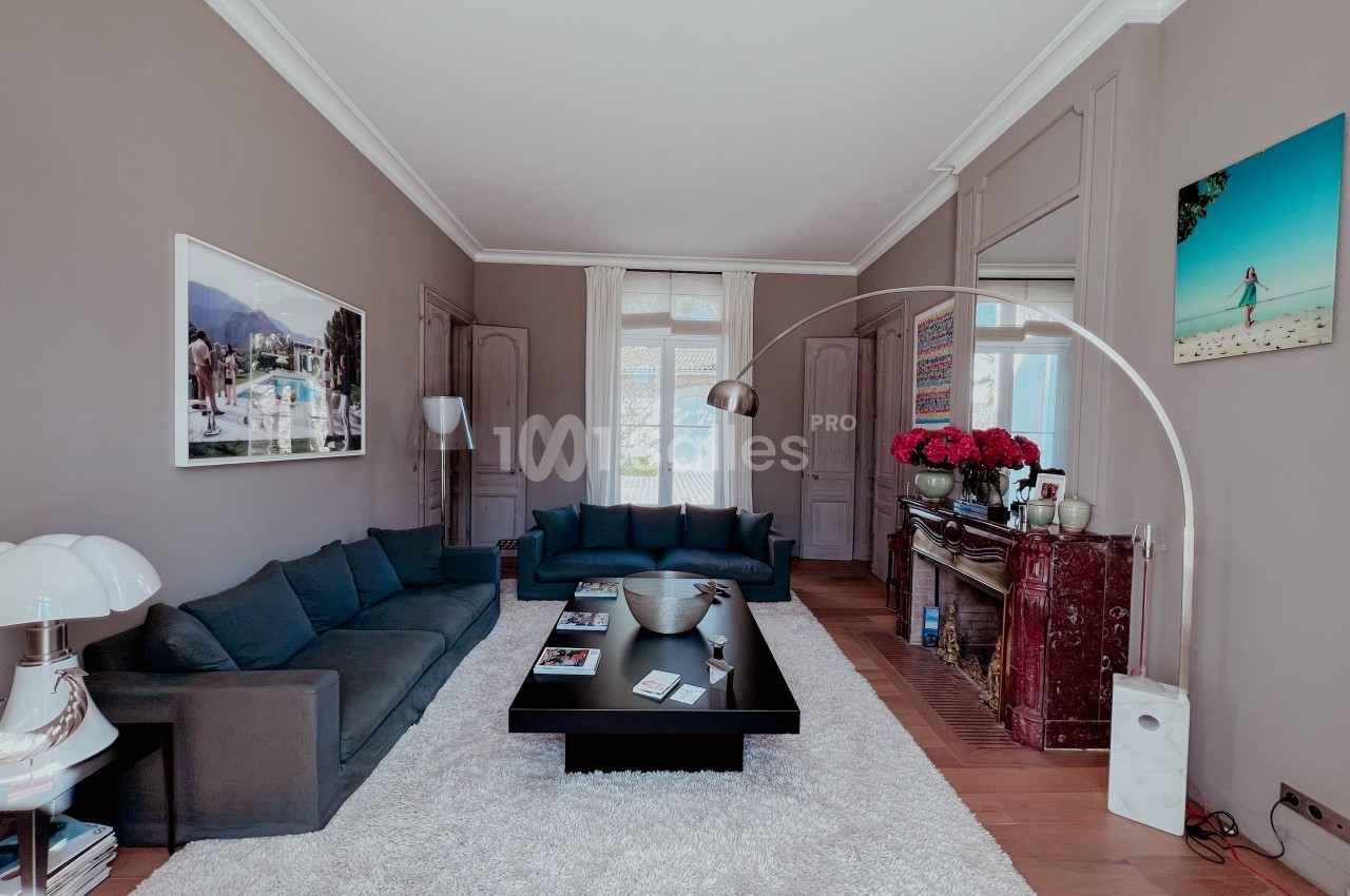 Salon élégant avec canapé gris, table basse noire, cheminée en marbre rouge, et décoration soignée dans un intérieur…