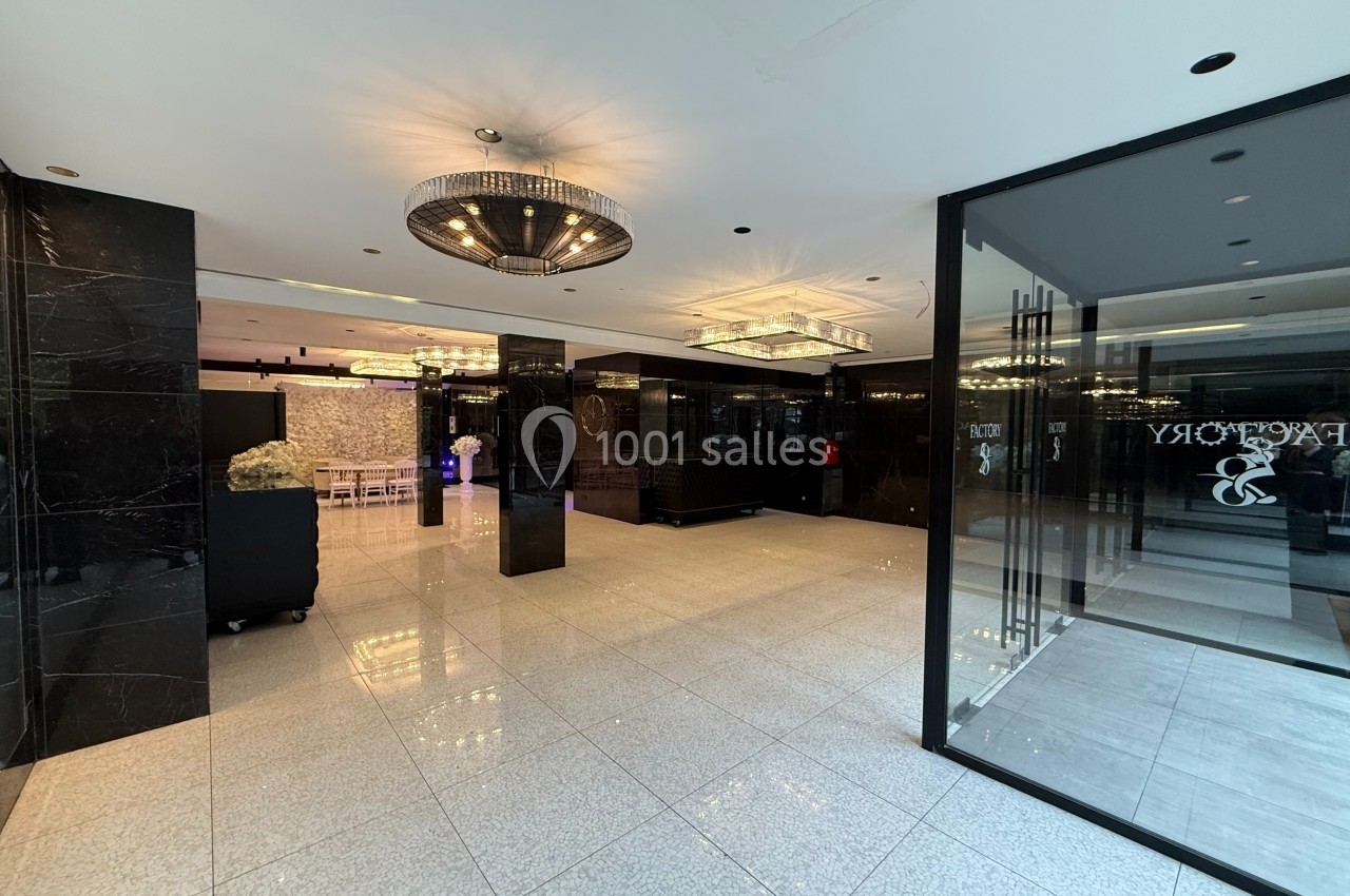 Hall d'entrée moderne avec sol en carrelage brillant, murs noirs, lustres et portes vitrées.