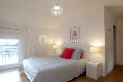 Deux lits simples avec housses rouges à pois blancs dans une chambre lumineuse décorée de touches rouges et blanches.