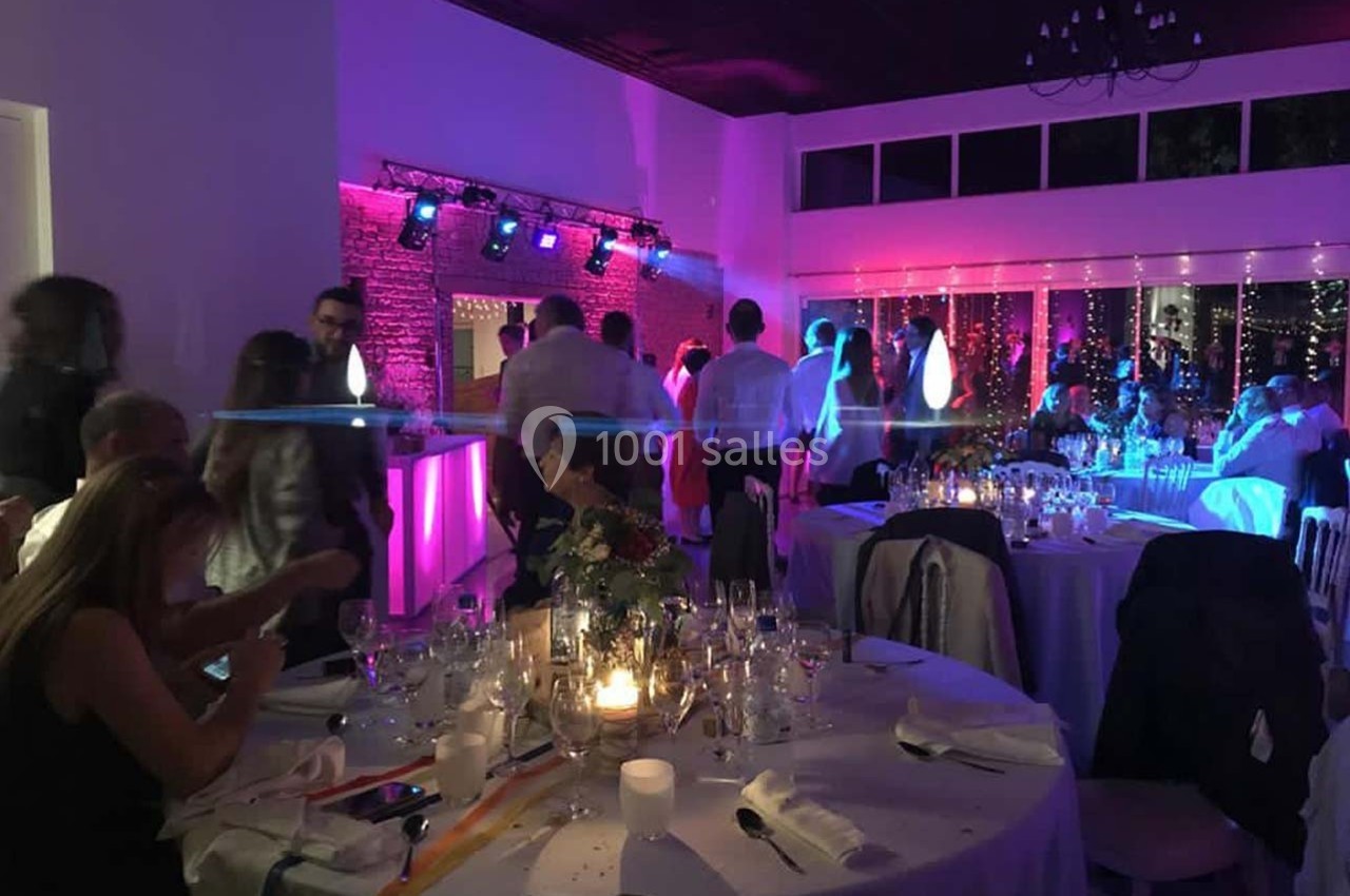 Location salle Sainte-Foy-d'Aigrefeuille (Haute-Garonne) - Les Ecuries de Ronsac #18 Salle de réception éclairée avec des lumières colorées, des invités debout et des tables dressées pour un événement.