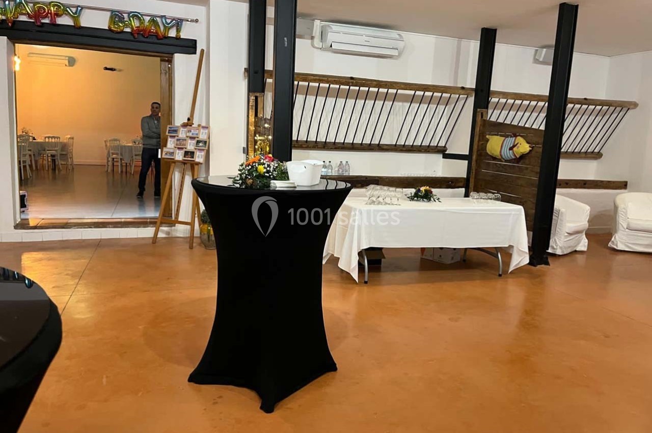 Location salle Sainte-Foy-d'Aigrefeuille (Haute-Garonne) - Les Ecuries de Ronsac #7 Salle de réception avec table haute noire au premier plan, buffet dressé et décorations murales en arrière-plan.