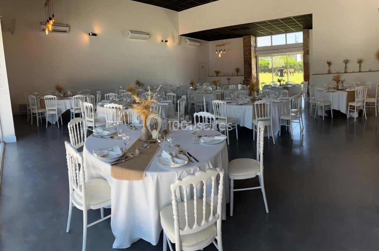 Location salle Sainte-Foy-d'Aigrefeuille (Haute-Garonne) - Les Ecuries de Ronsac #8 Salle de réception lumineuse avec tables rondes dressées, nappes blanches et décorations florales naturelles.