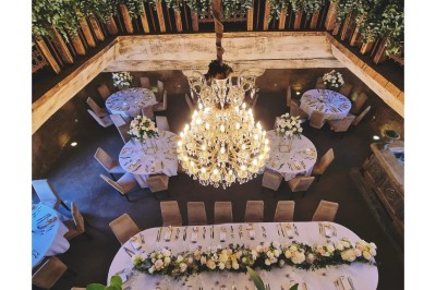 Cour pavée d'un bâtiment en pierre éclairé par des lumières extérieures, entouré d'arbres et de bâtiments annexes, de nuit.