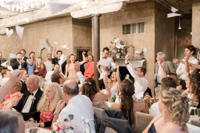 Cour pavée d'un bâtiment en pierre éclairé par des lumières extérieures, entouré d'arbres et de bâtiments annexes, de nuit.
