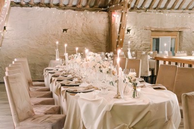 Cour pavée d'un bâtiment en pierre éclairé par des lumières extérieures, entouré d'arbres et de bâtiments annexes, de nuit.