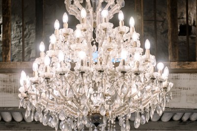 Cour pavée d'un bâtiment en pierre éclairé par des lumières extérieures, entouré d'arbres et de bâtiments annexes, de nuit.