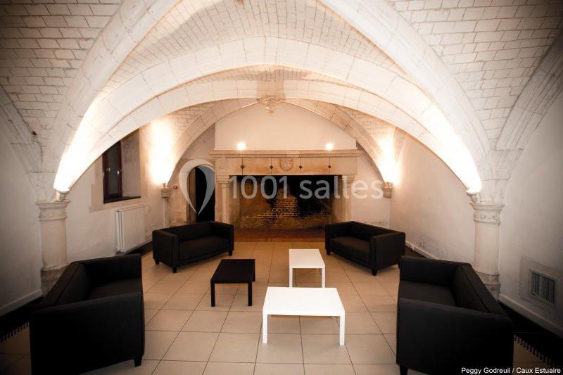 Location salle Saint-Romain-de-Colbosc (Seine-Maritime) - Château de Gromesnil #13 Salle voûtée avec cheminée ancienne, mobilier moderne comprenant canapés noirs et tables basses blanches.