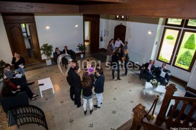Miniature Location salle Saint-Romain-de-Colbosc (Seine-Maritime) - Château de Gromesnil #14 Pelouse verdoyante bordée d'arbres hauts sous un ciel bleu clair, avec une petite structure en briques à gauche.