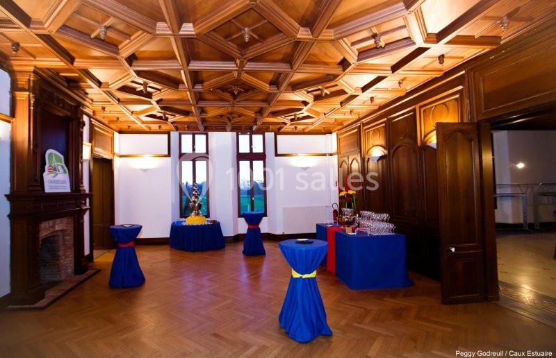 Location salle Saint-Romain-de-Colbosc (Seine-Maritime) - Château de Gromesnil #16 Salle avec parquet, plafond à caissons en bois, tables hautes décorées et buffet installé près d'une cheminée.