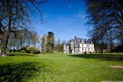 Miniature Location salle Saint-Romain-de-Colbosc (Seine-Maritime) - Château de Gromesnil #11 Pelouse verdoyante bordée d'arbres hauts sous un ciel bleu clair, avec une petite structure en briques à gauche.