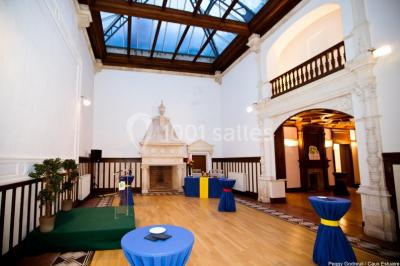 Pelouse verdoyante bordée d'arbres hauts sous un ciel bleu clair, avec une petite structure en briques à gauche.