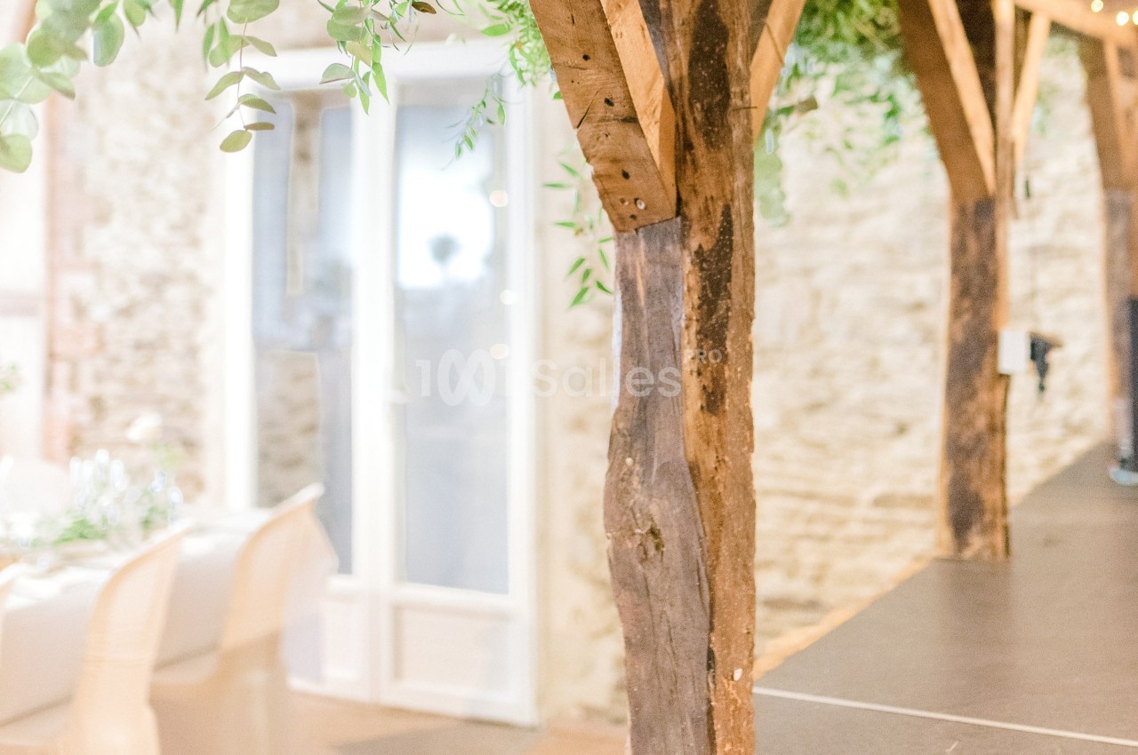Structure en bois rustique avec des plantes suspendues, près d'une table dressée et d'une porte vitrée.