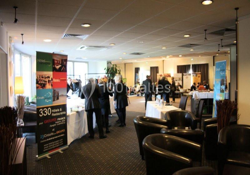 Des personnes discutent dans une salle de conférence avec des stands d'exposition et des affiches promotionnelles.