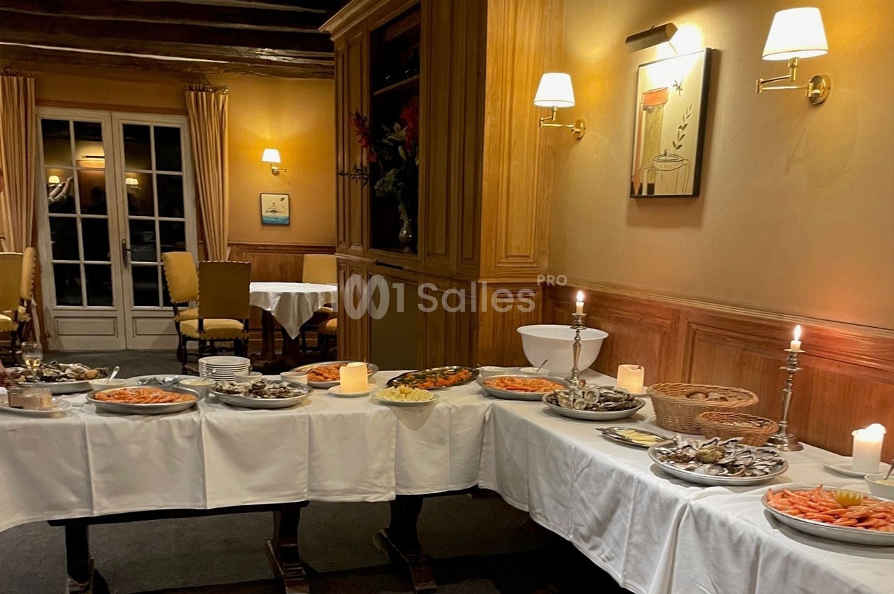 Buffet de fruits de mer et plats variés disposés sur une longue table dans une salle éclairée et chaleureuse.