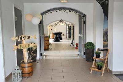 Vue aérienne d'un complexe avec plusieurs bâtiments, un jardin central, un parking et des zones identifiées par des noms.