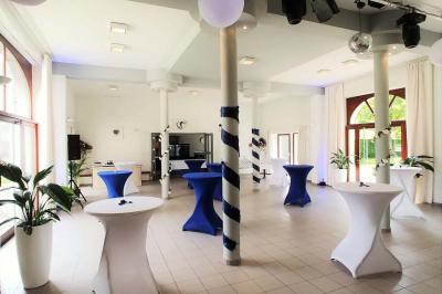 Vue aérienne d'un complexe avec plusieurs bâtiments, un jardin central, un parking et des zones identifiées par des noms.